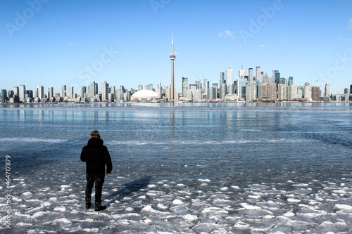 Man standing on Frozen Lake Ontario with Toronto skyline