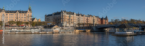 The landing of the bridge Djurgårdsbron in the district Östermalm with boat piers and a channel in Stockholm a colorful autumn day