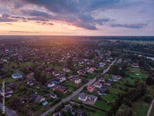 Late evening sunset areal drone view of suburbs with many small private houses and gardens.