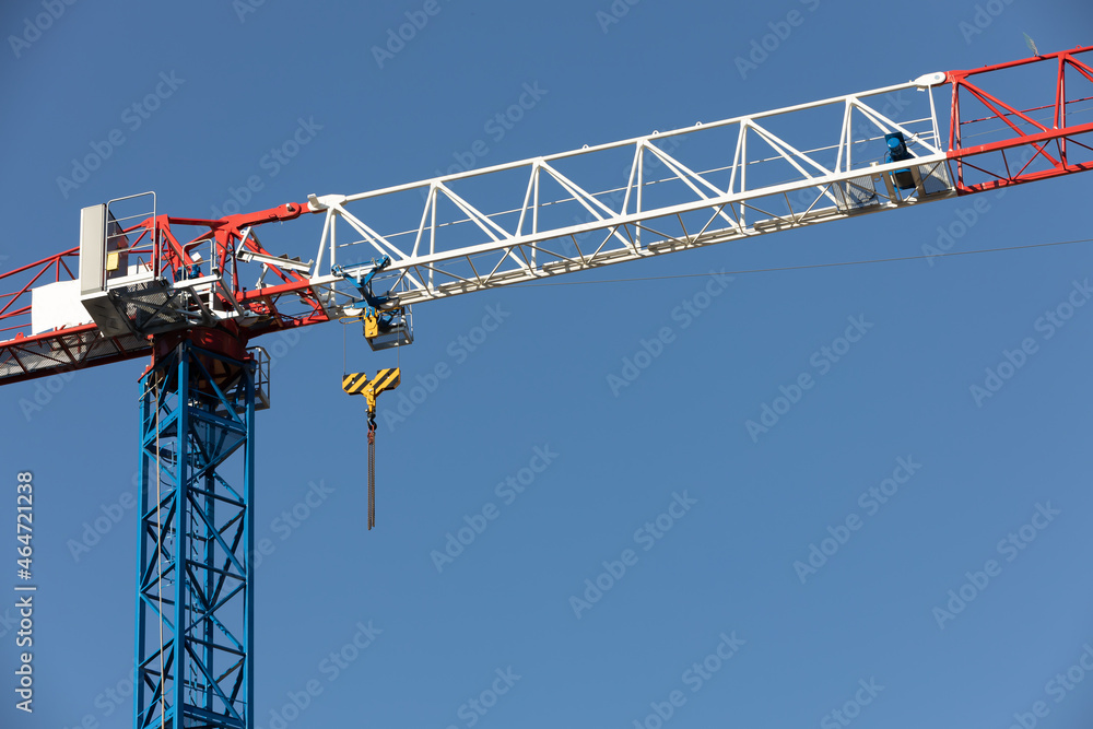blue, white and red construction crane against the sky
