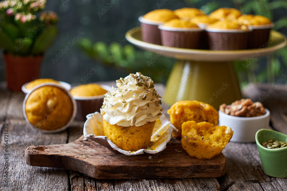 Pumpkin muffins and cupcake with white chocolate and walnuts. Side view, wooden and green background, horizontal. Pumpkin muffins and cupcake with white chocolate and walnuts. Side view, wooden and green background, horizontal.