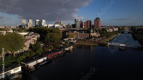 Aerial ascending movement showing Muntgebouw revealing skyline of Dutch city Utrecht with financial and central train station area in the background with canal and floating homes in the foreground photo