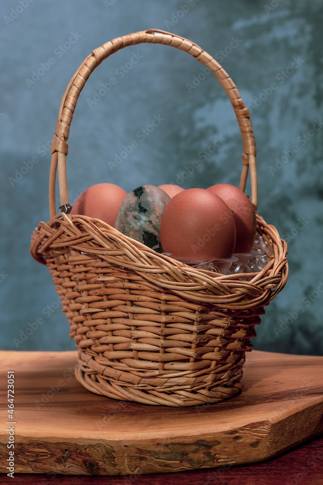 A wicker basket contains eggs, one of which is made of volcanic stone A wicker basket contains eggs, one of which is made of volcanic stone