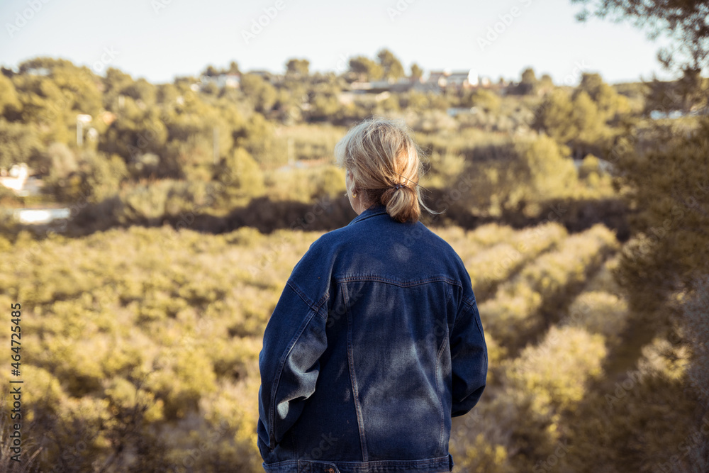 Woman in denim jacket walking with her dog through her forest