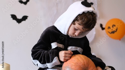 Boy in costume skeletone draws face pumpkin for Halloween, concept for Halloween festival. photo