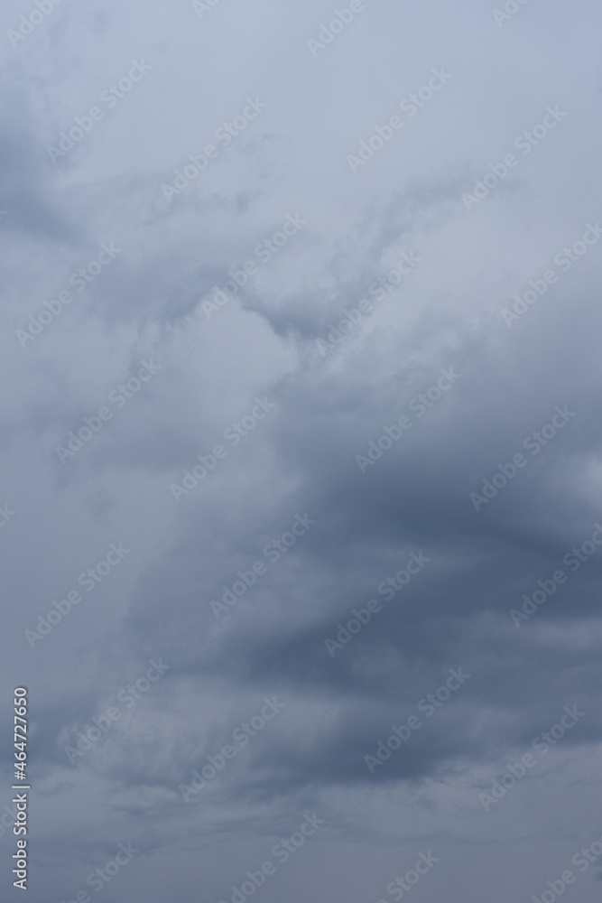 Fototapeta premium Gray cloudy sky with beautiful volumetric fluffy clouds, vertical frame. A natural natural sky background to blend with your photos.
