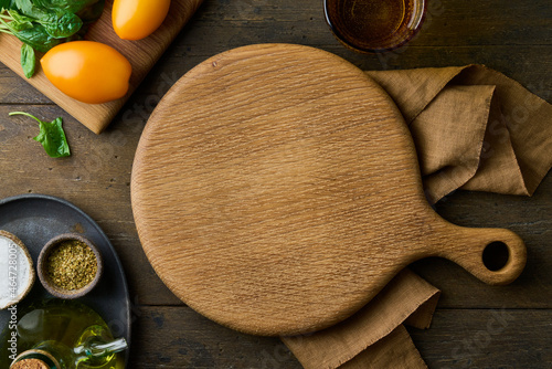 фотографія Wooden round cutting board on dark brown wood background