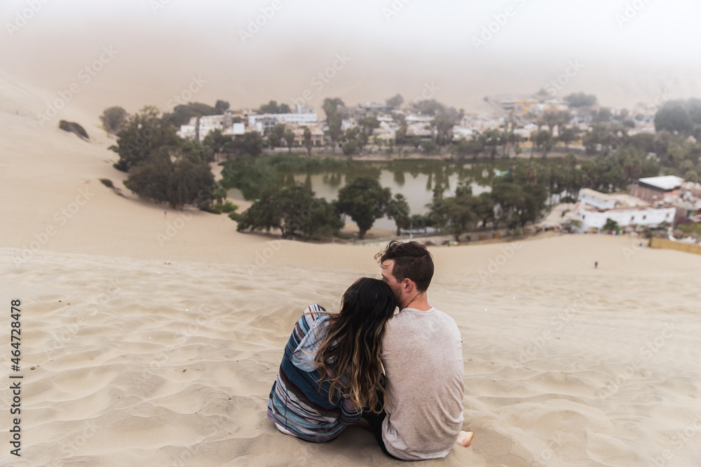 Cute couple sitting in front of Huacachina Desert Oasis