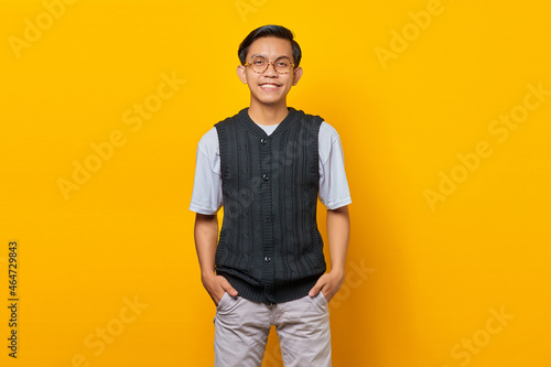 Portrait of handsome asian young man smiling looking at camera isolated on yellow background