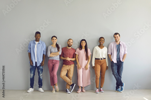 Quadro em tela Portrait of a group of smiling multiracial people standing in a row on a light wall background