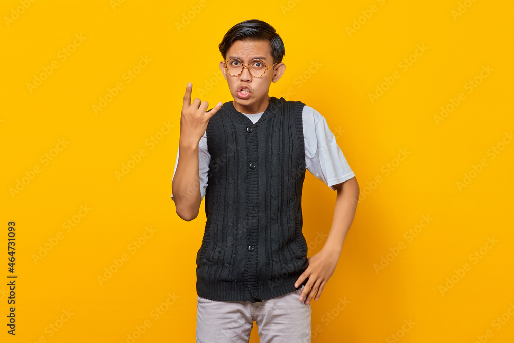 Portrait of young asian man wearing casual clothes screaming with crazy expression doing rock symbol with hands up Portrait of young asian man wearing casual clothes screaming with crazy expression doing rock symbol with hands up