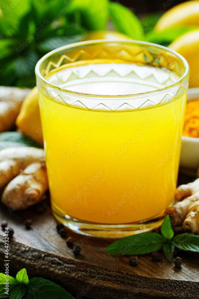 Immune booster antivirus drink, turmeric with ginger, lemon, mint and spices hot winter tea on wooden rustic background, closeup, natural medicine and naturopathy concept Immune booster antivirus drink, turmeric with ginger, lemon, mint and spices hot winter tea on wooden rustic background, closeup, natural medicine and naturopathy concept