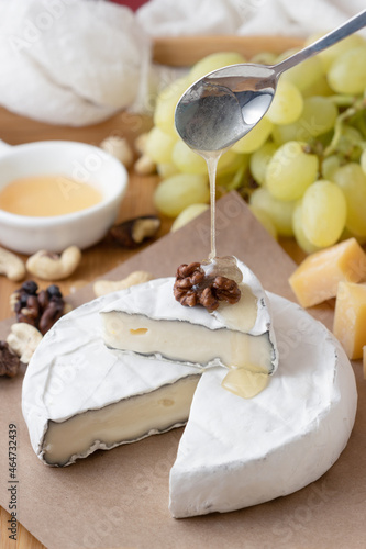 Honey pours from a spoon on brie cheese