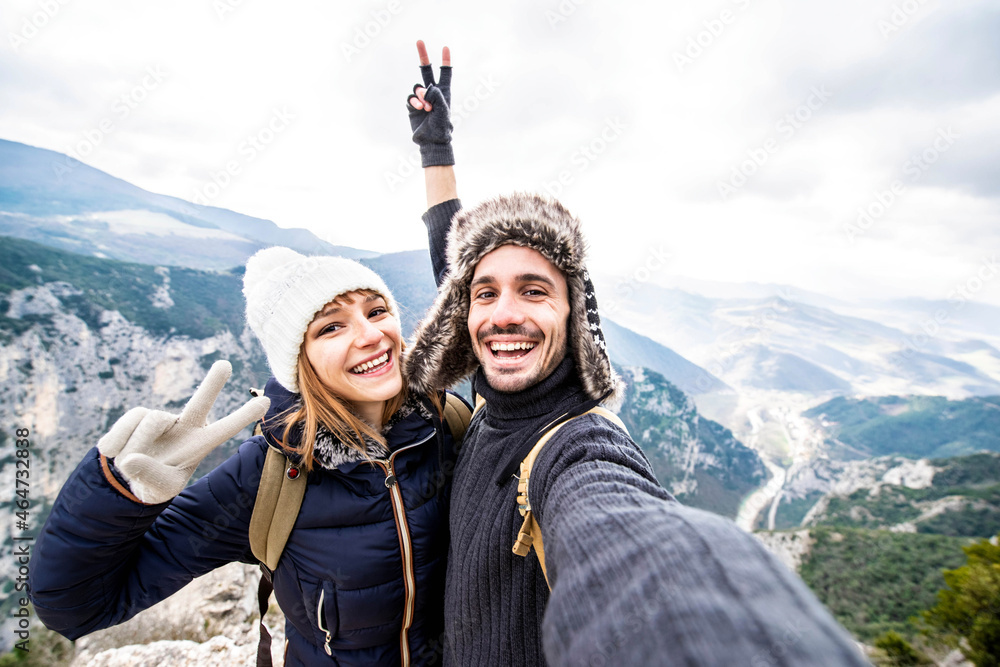 Traveler couple with backpacks taking selfie portrait hiking mountains - Happy guy and girl having fun outdoors - obrazy, fototapety, plakaty 