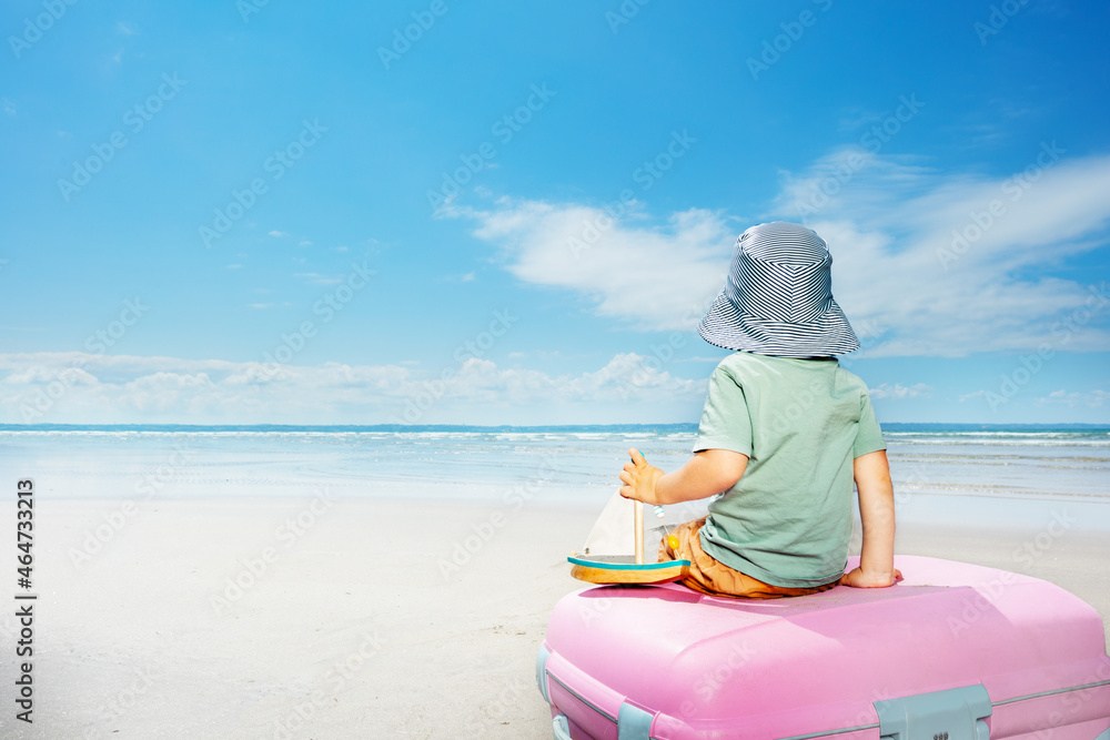 Nice sailor boy on baggage suitcase with toy boat