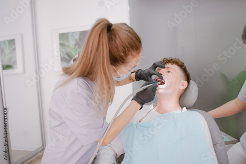 a patient with an open mouth sits at an orthodontist's appointment, performs a bracket system, a bracket system on a tooth, installs ligature braces, drills in the mouth. Anapa city September 24, 2021