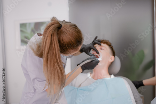 a patient with an open mouth sits at an orthodontist's appointment, performs a bracket system, a bracket system on a tooth, installs ligature braces, drills in the mouth. Anapa city September 24, 2021