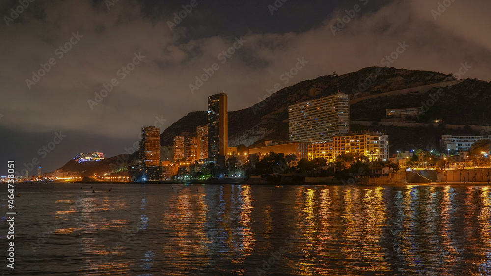 Panorámica nocturna de las calitas de la Playa de la Albufereta y sus rascacielos con reflejos en el mar