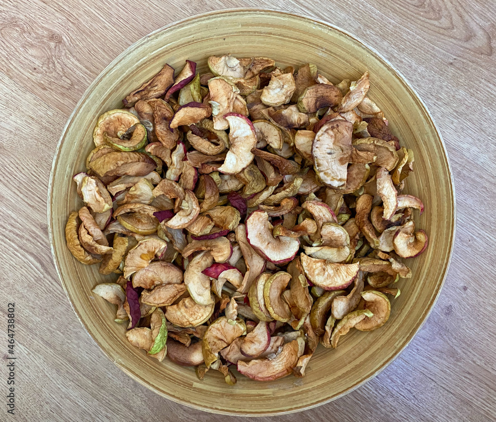 Dried apples in a plate close-up. Dried fruits from apples are in a wooden plate Dried apples in a plate close-up. Dried fruits from apples are in a wooden plate
