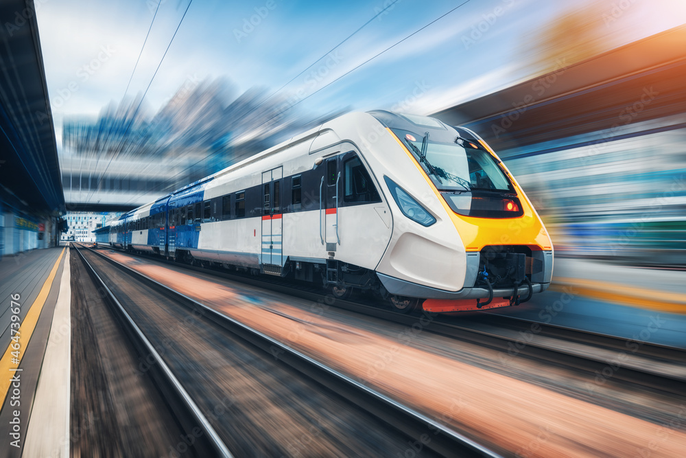 High speed train in motion on the railway station at sunset - obrazy, fototapety, plakaty 