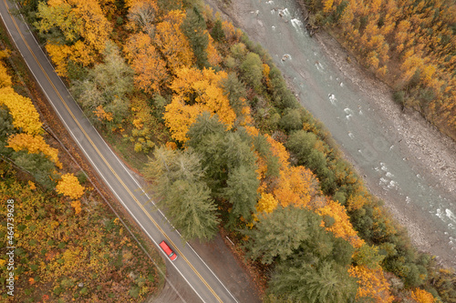 Overhead View of an Automobile Traveling on a Roadway Next to a River During the Fall Season. A car travels along the colorful, autumnal, Mt. Baker Highway alongside the beautiful Nooksack River. 