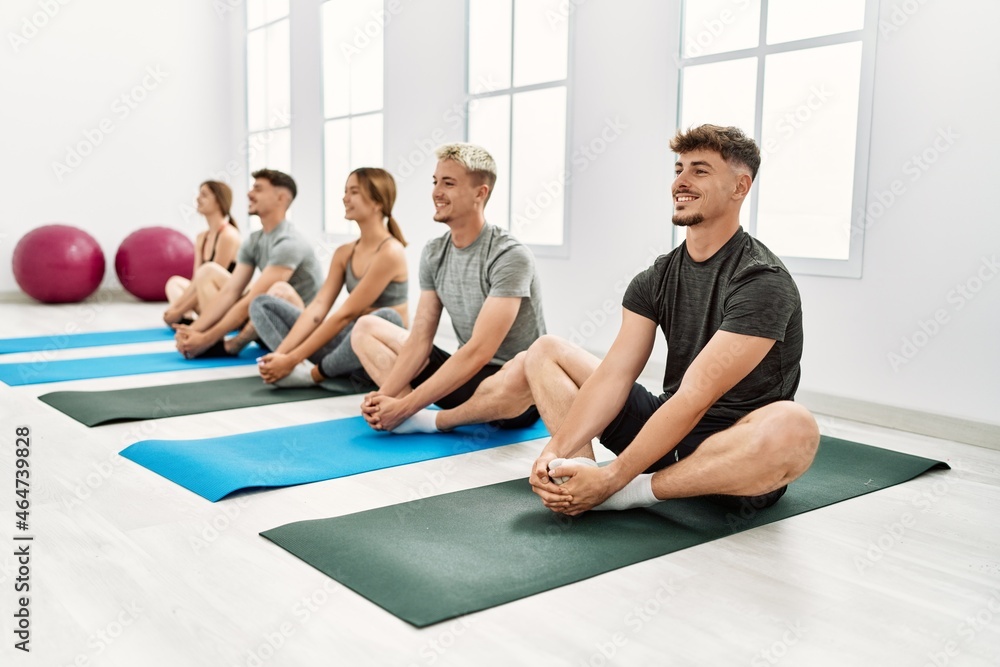 Fototapeta premium Group of young hispanic people smiling happy stretching at sport center.