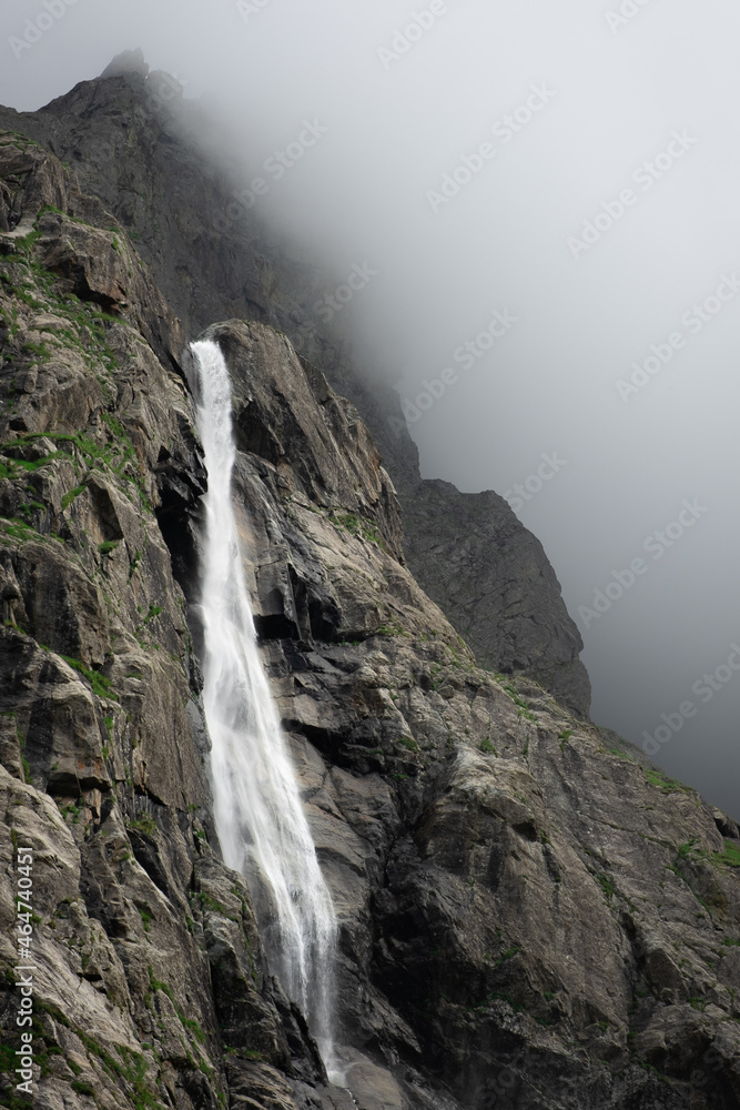Beautiful view of Midagrabin waterfall in sunlight in cloudy summer weather. Caucasus mountains. Russia. North Ossetia Alania