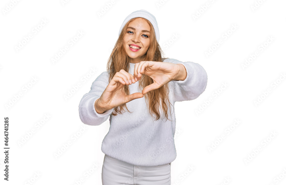 Young caucasian girl wearing wool sweater and winter cap smiling in love doing heart symbol shape with hands. romantic concept. Young caucasian girl wearing wool sweater and winter cap smiling in love doing heart symbol shape with hands. romantic concept.