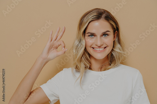 Wallpaper Mural Positive cute blonde young woman in white tshirt shows OK sign with one hand Torontodigital.ca