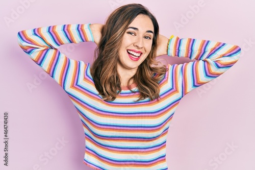 Young hispanic girl wearing casual clothes relaxing and stretching, arms and hands behind head and neck smiling happy