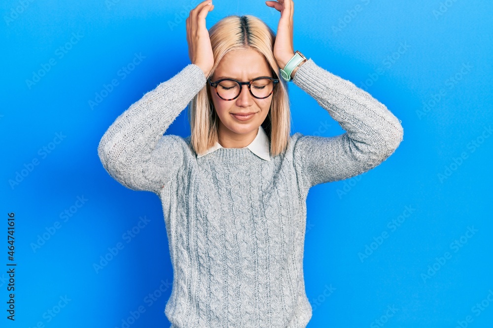 Beautiful blonde woman wearing glasses suffering from headache desperate and stressed because pain and migraine. hands on head. Beautiful blonde woman wearing glasses suffering from headache desperate and stressed because pain and migraine. hands on head.