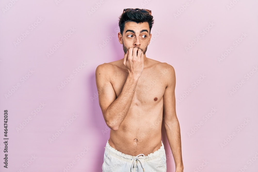 Fototapeta premium Young hispanic man wearing swimwear shirtless looking stressed and nervous with hands on mouth biting nails. anxiety problem.