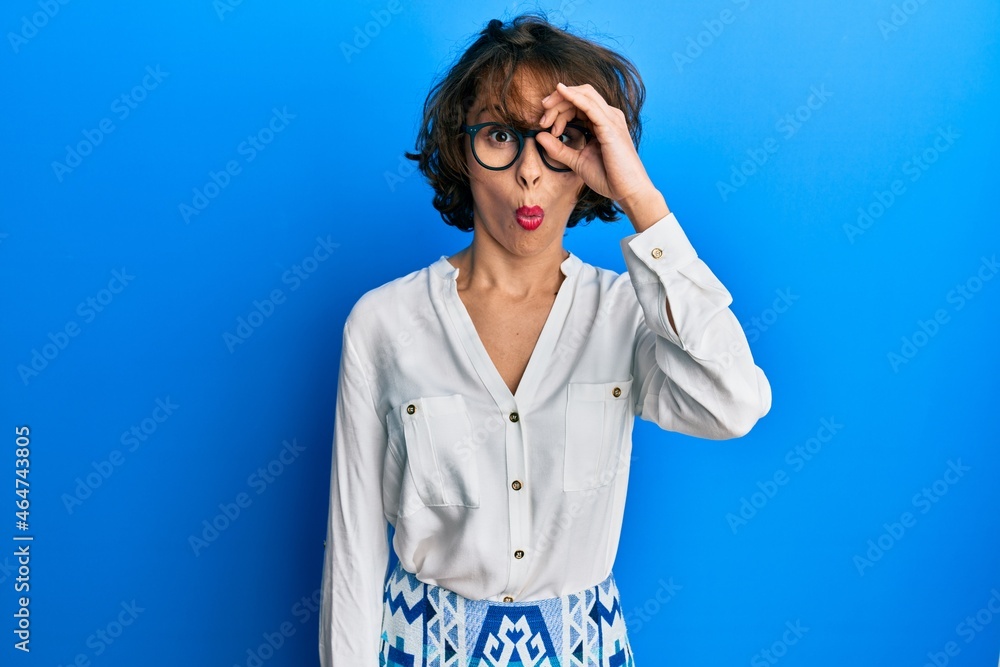 Young brunette woman wearing casual clothes and glasses doing ok gesture shocked with surprised face, eye looking through fingers. unbelieving expression. Young brunette woman wearing casual clothes and glasses doing ok gesture shocked with surprised face, eye looking through fingers. unbelieving expression.