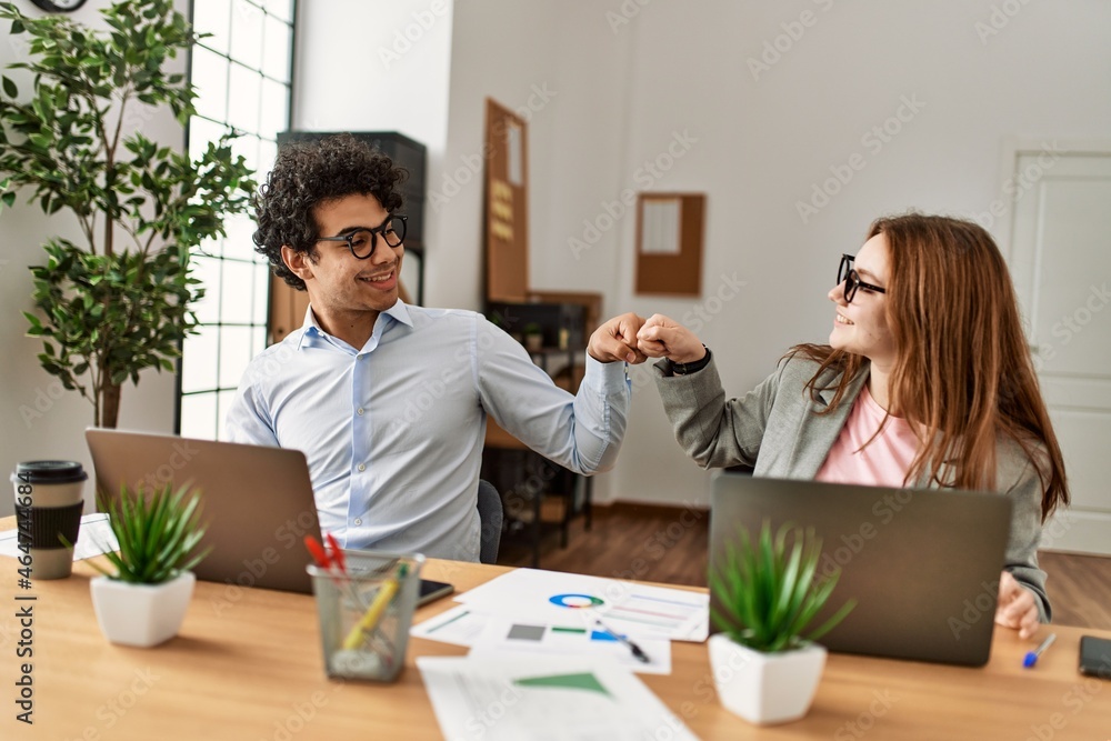 Two business workers smiling happy bump fists at the office. Two business workers smiling happy bump fists at the office.