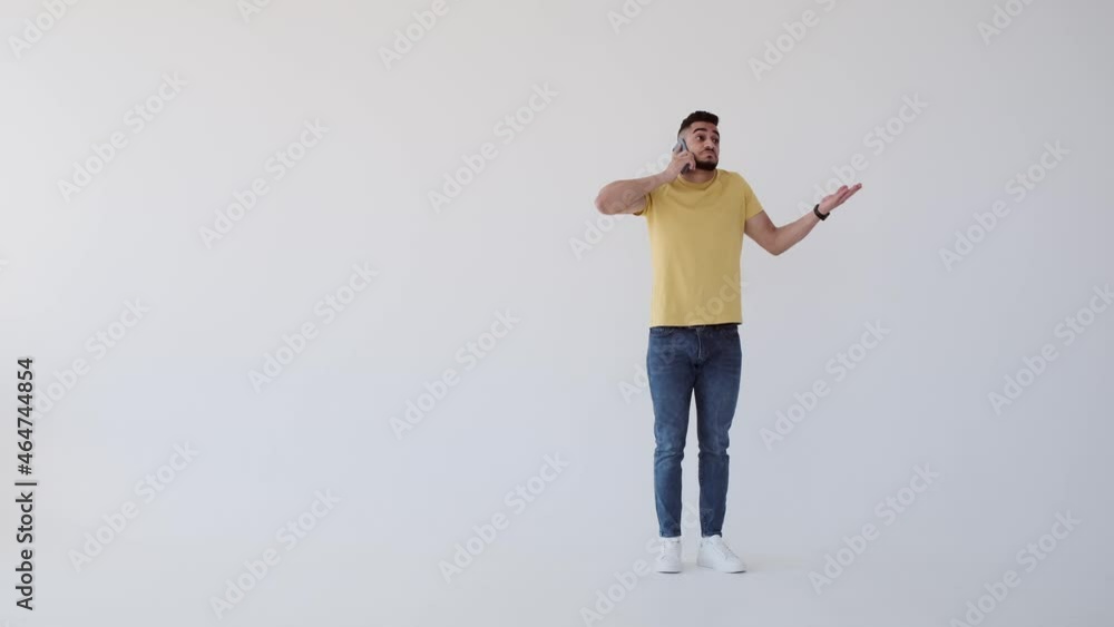 Young man walking while talking on mobile phone over white background Young man walking while talking on mobile phone over white background