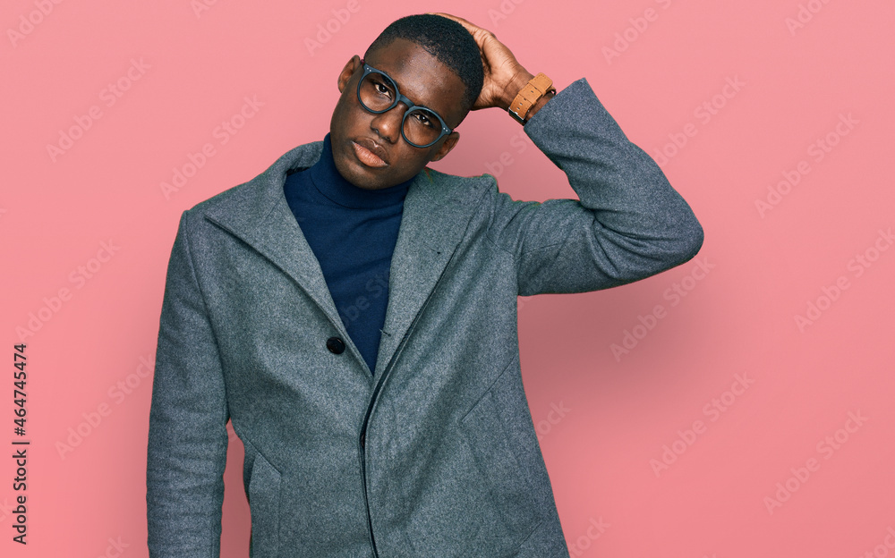 Fototapeta premium Young african american man wearing business clothes and glasses confuse and wondering about question. uncertain with doubt, thinking with hand on head. pensive concept.