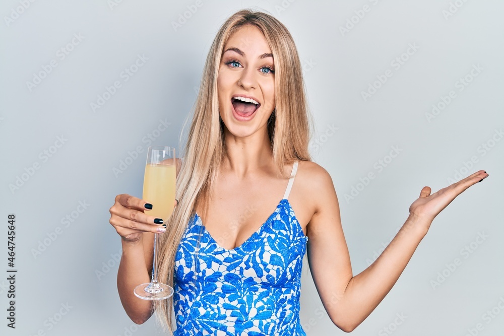 Young caucasian woman drinking a glass of sparkling champagne celebrating victory with happy smile and winner expression with raised hands Young caucasian woman drinking a glass of sparkling champagne celebrating victory with happy smile and winner expression with raised hands