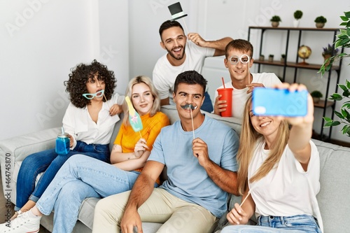Group of young friends having party using funny costume accessories at home.