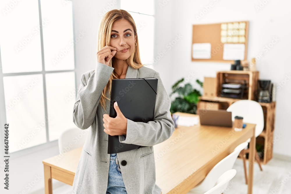 Obraz premium Blonde business woman at the office mouth and lips shut as zip with fingers. secret and silent, taboo talking