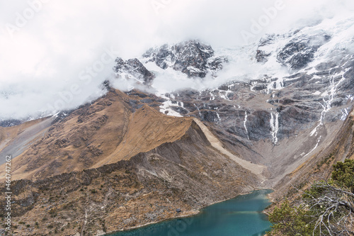 Humantay lagoon surrounded by snow-capped mountains and salcantay glaciers in the Andes mountain range of Peru on a sunny day with clouds