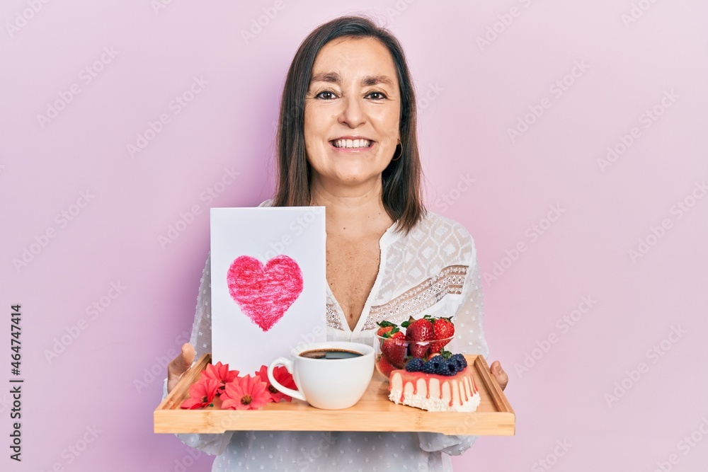 Middle age hispanic woman holding tray with breakfast food and heart draw smiling with a happy and cool smile on face. showing teeth. Middle age hispanic woman holding tray with breakfast food and heart draw smiling with a happy and cool smile on face. showing teeth.