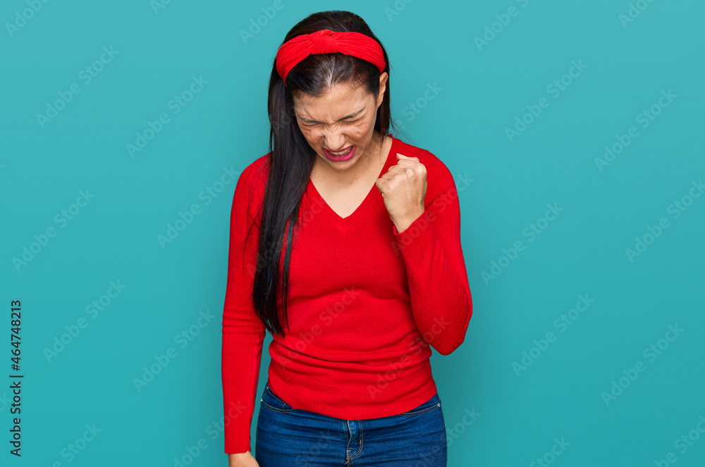 Young hispanic woman wearing casual clothes angry and mad raising fist frustrated and furious while shouting with anger. rage and aggressive concept. Young hispanic woman wearing casual clothes angry and mad raising fist frustrated and furious while shouting with anger. rage and aggressive concept.