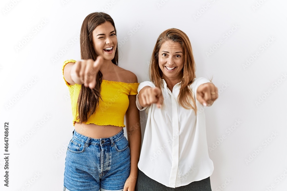 Mother and daughter together standing together over isolated background pointing to you and the camera with fingers, smiling positive and cheerful Mother and daughter together standing together over isolated background pointing to you and the camera with fingers, smiling positive and cheerful