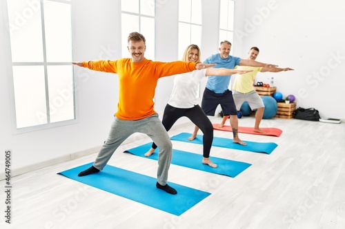 Group of middle age people training yoga at sport center.