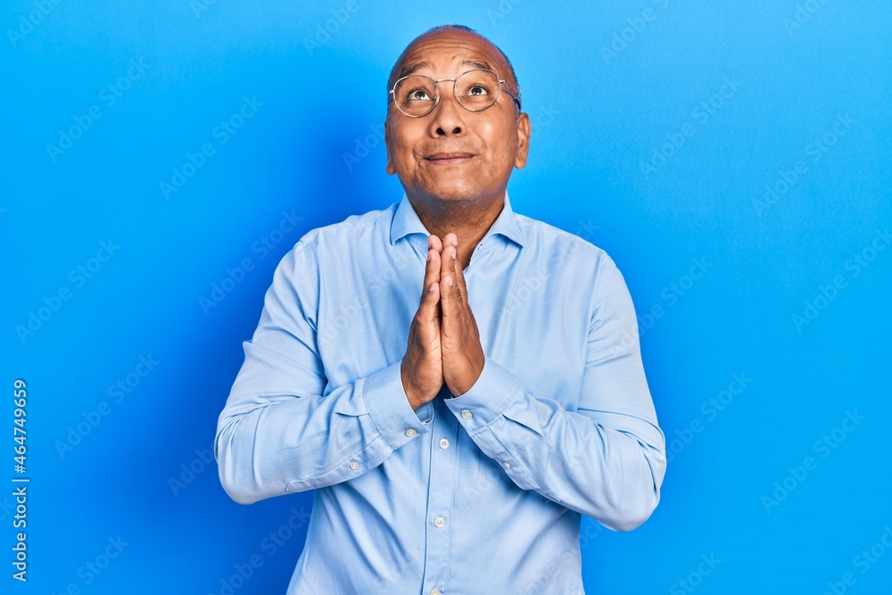 Middle age latin man wearing casual clothes and glasses begging and praying with hands together with hope expression on face very emotional and worried. begging. Middle age latin man wearing casual clothes and glasses begging and praying with hands together with hope expression on face very emotional and worried. begging.