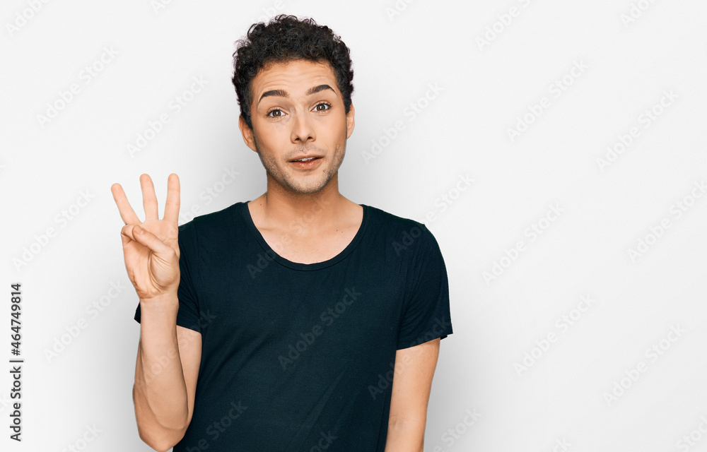 Young handsome man wearing casual black t shirt showing and pointing up with fingers number three while smiling confident and happy. Young handsome man wearing casual black t shirt showing and pointing up with fingers number three while smiling confident and happy.