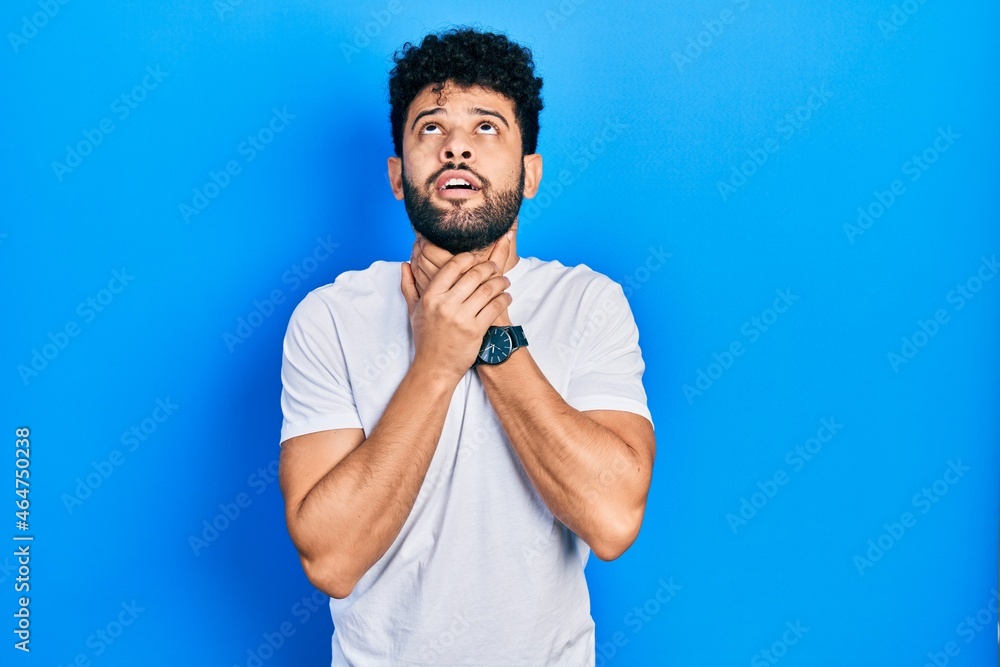 Young arab man with beard wearing casual white t shirt shouting suffocate because painful strangle. health problem. asphyxiate and suicide concept. Young arab man with beard wearing casual white t shirt shouting suffocate because painful strangle. health problem. asphyxiate and suicide concept.