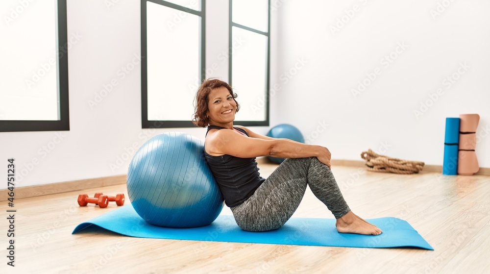 Middle age hispanic sporty woman smiling happy training with fit ball at sport center. Middle age hispanic sporty woman smiling happy training with fit ball at sport center.