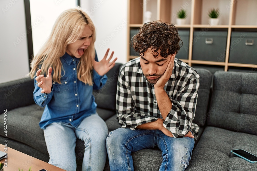 Young couple sitting on the sofa discussing at home. Young couple sitting on the sofa discussing at home.