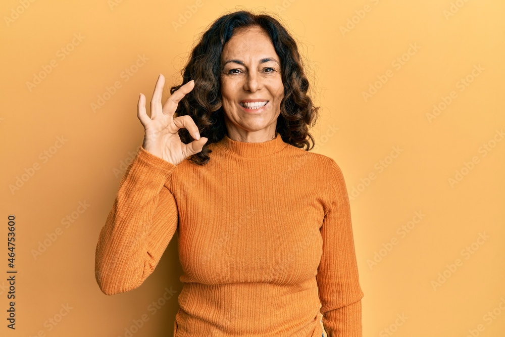 Middle age hispanic woman wearing casual clothes smiling positive doing ok sign with hand and fingers. successful expression. Middle age hispanic woman wearing casual clothes smiling positive doing ok sign with hand and fingers. successful expression.